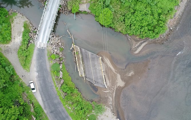 An aerial photo of a section of road that has been washed out by flood waters.