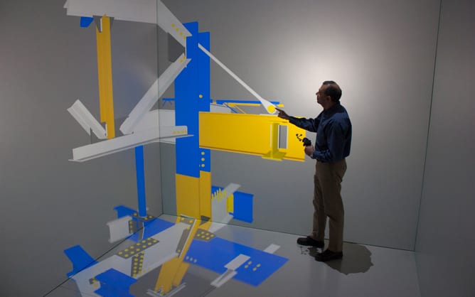 A person standing in a virtual reality environment manipulating a colorful structure model.