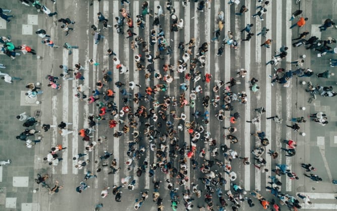 An aerial photo of a large crowd of people using a busy crosswalk.